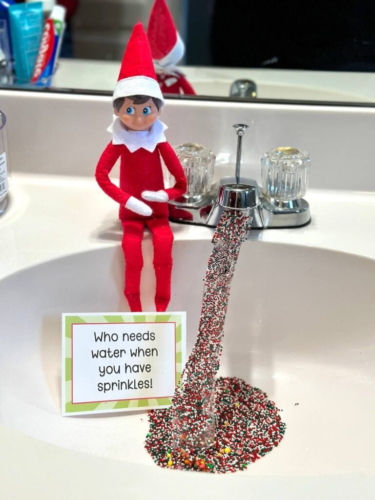 Elf on the Shelf with sprinkles coming out of the sink faucet