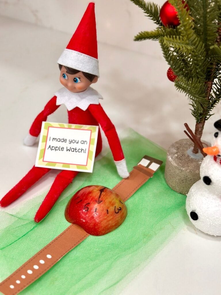 Elf on the Shelf with half and apple and a paper watch band
