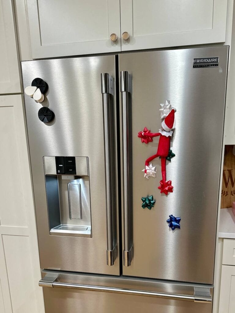 Elf on the Shelf climbing up bows on a refrigerator