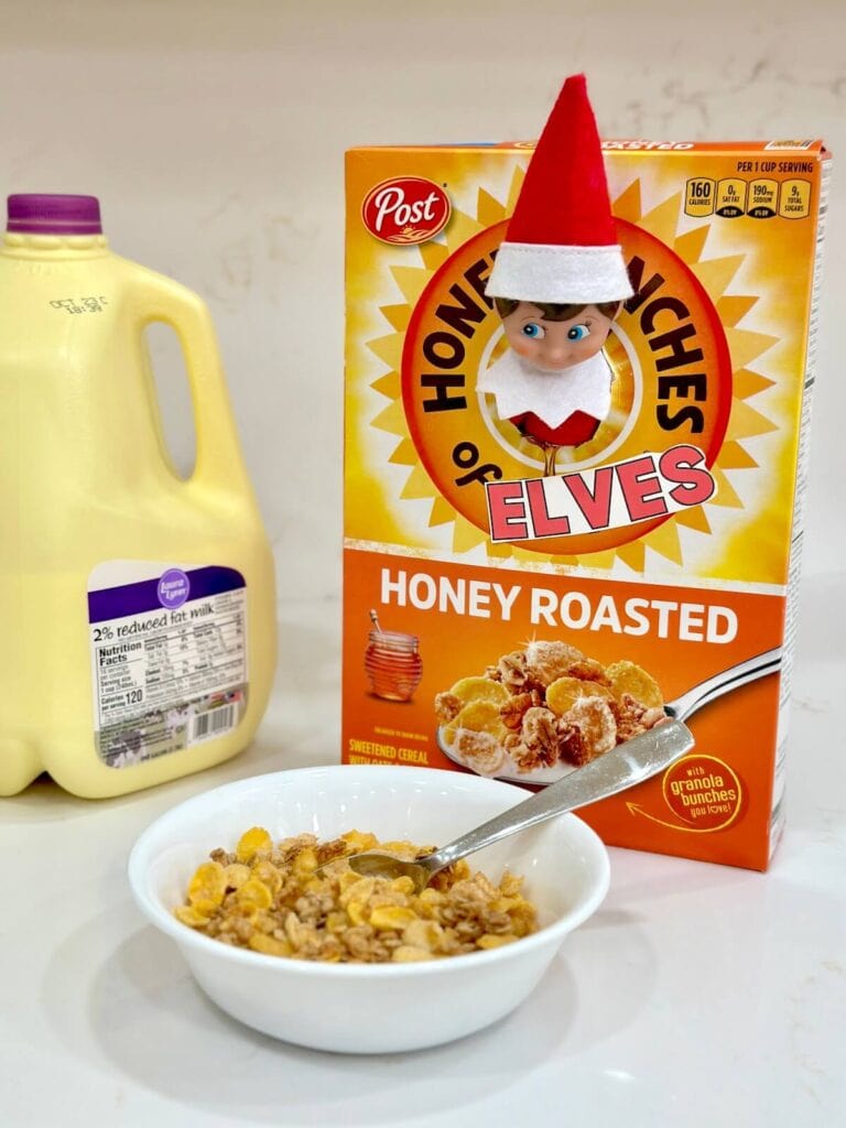 Elf on the Shelf with his head stuck through a cereal box