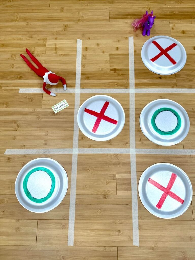 Elf on the Shelf playing tic tac toe with paper plates