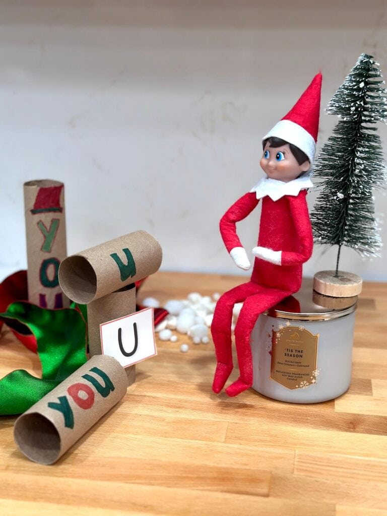 Elf on the Shelf watching toilet paper tubes with "U" drawn on them