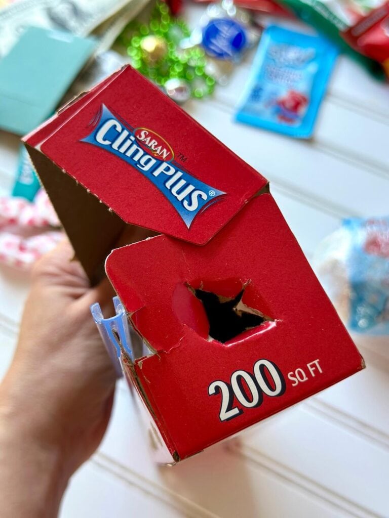 box of Saran wrap with cut holes in the side to hold the roll of plastic wrap in place