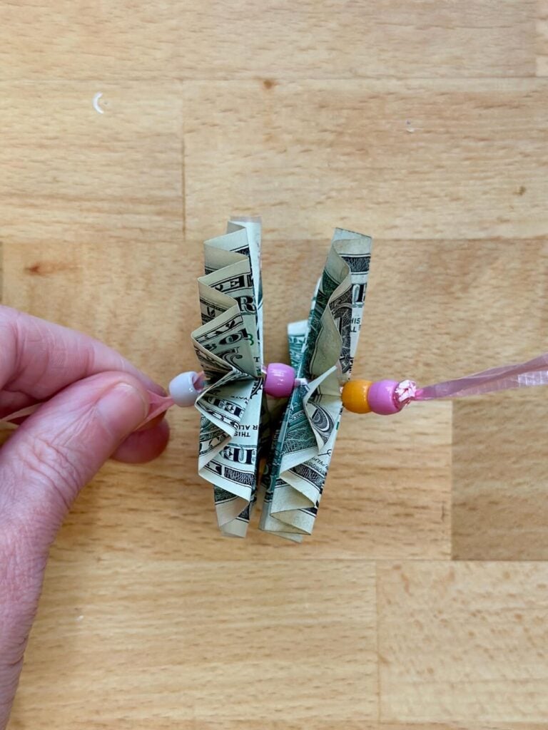 stringing dollar bills and beads for a money lei