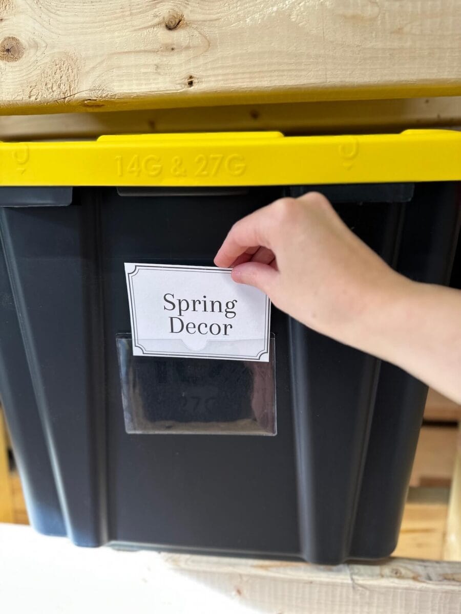 putting a free printable storage bin label on a storage tote