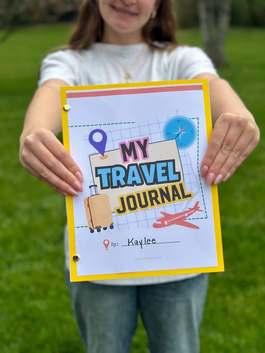 girl holding up a printable journal that says "my travel journal"