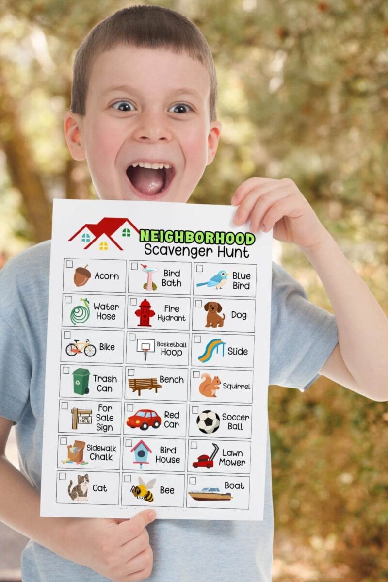 excited boy holding a neighborhood scavenger hunt checklist with pictures
