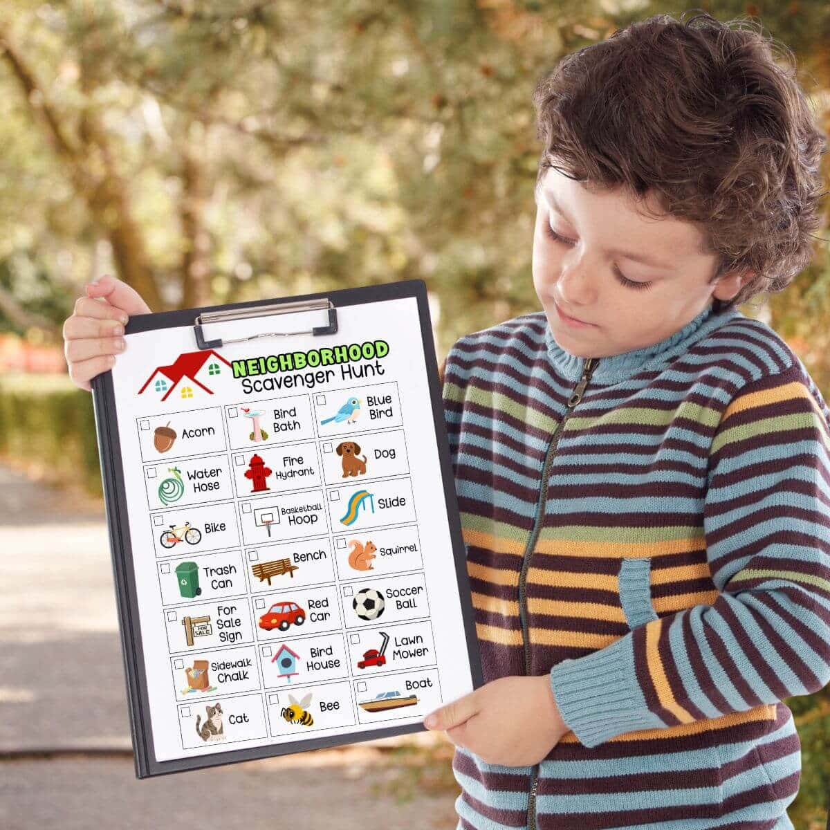 boy holding a clipboard outside with a neighborhood scavenger hunt paper