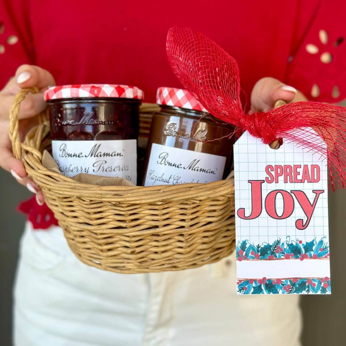 basket with jars of jam and a Christmas gift tag that says "Spread Joy"