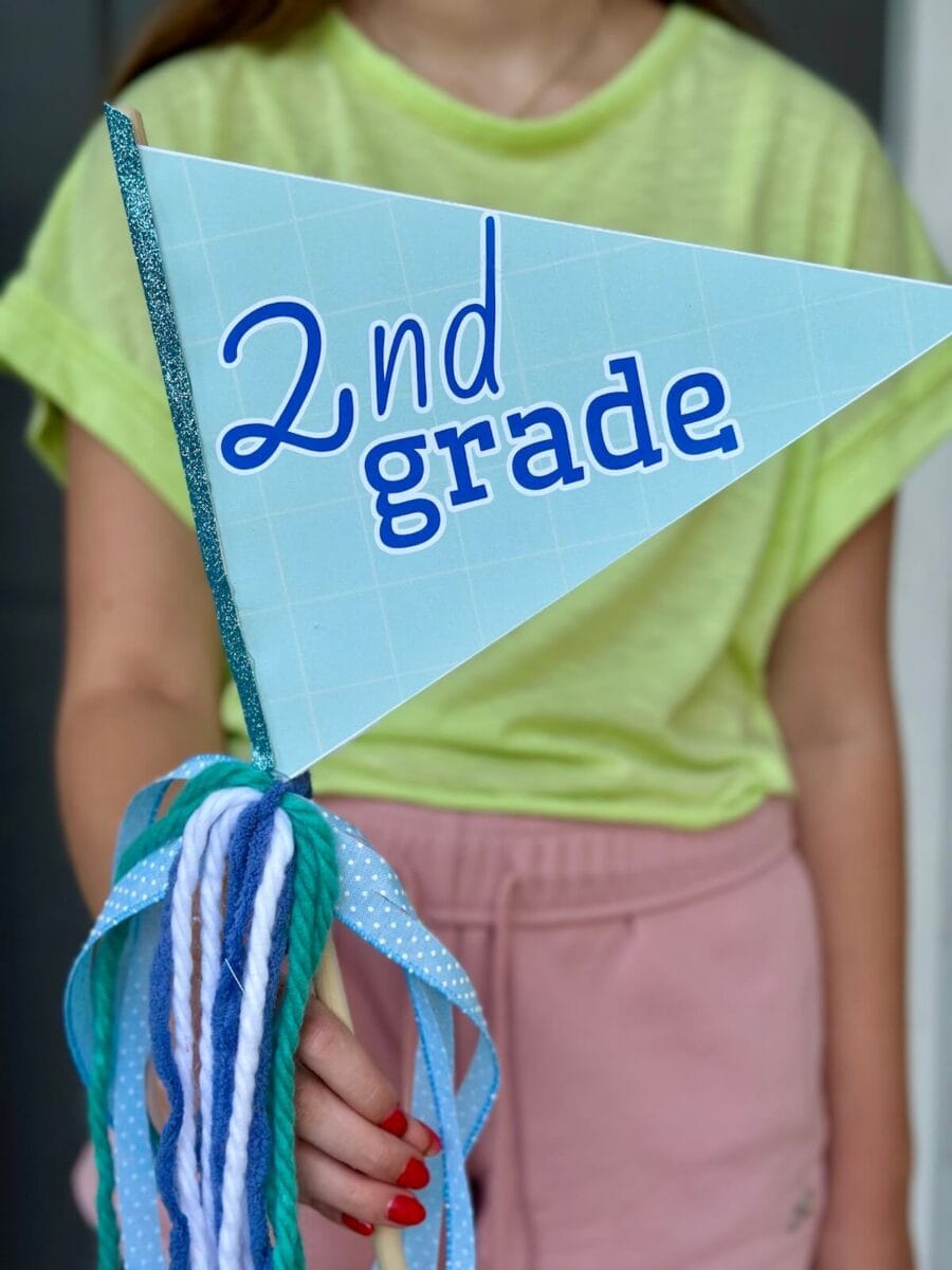 girl holding a pennant flag that says "2nd grade"