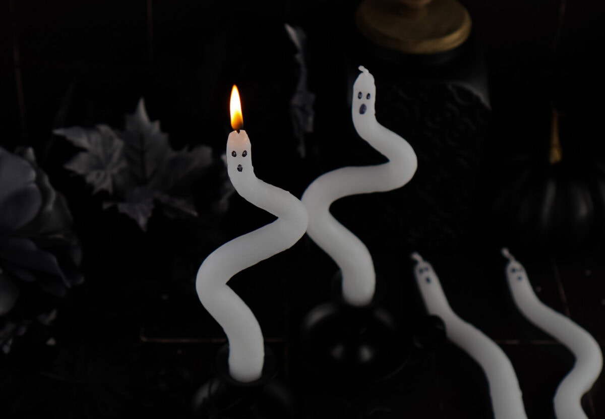 ghost candles made using white taper candles with black marker ghost faces