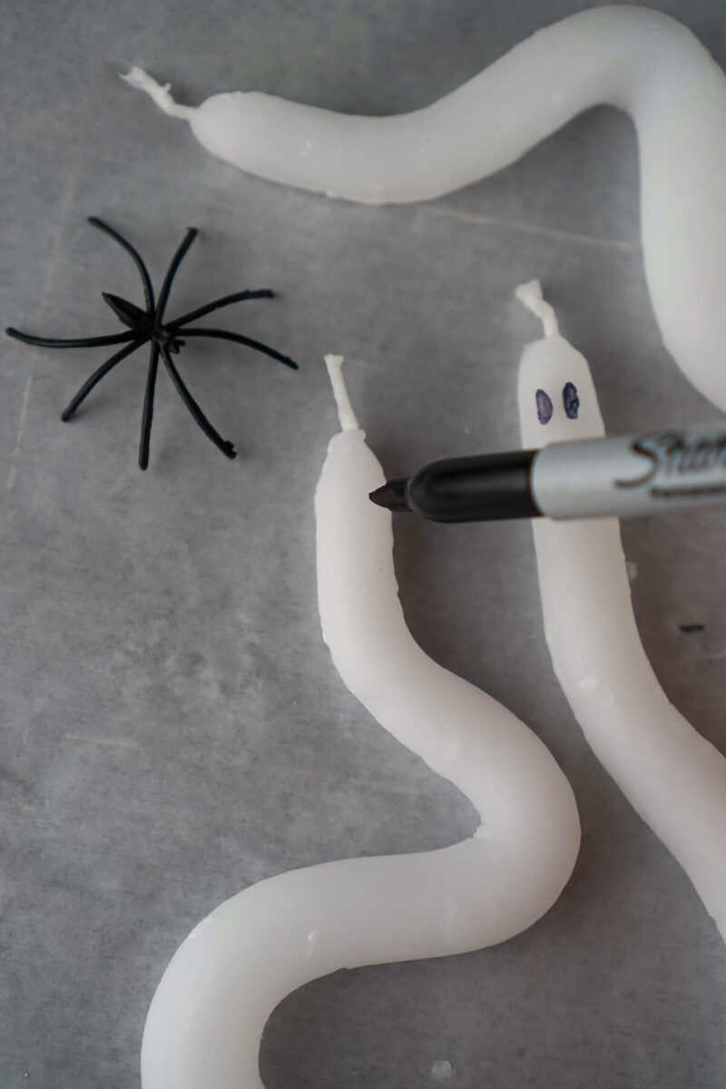 using a black Sharpie marker to draw ghost faces on white candles