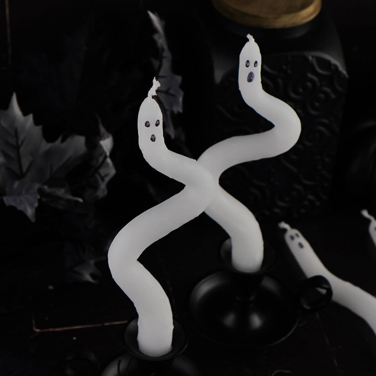 DIY ghost candles made using bent white taper candles with black marker ghost faces